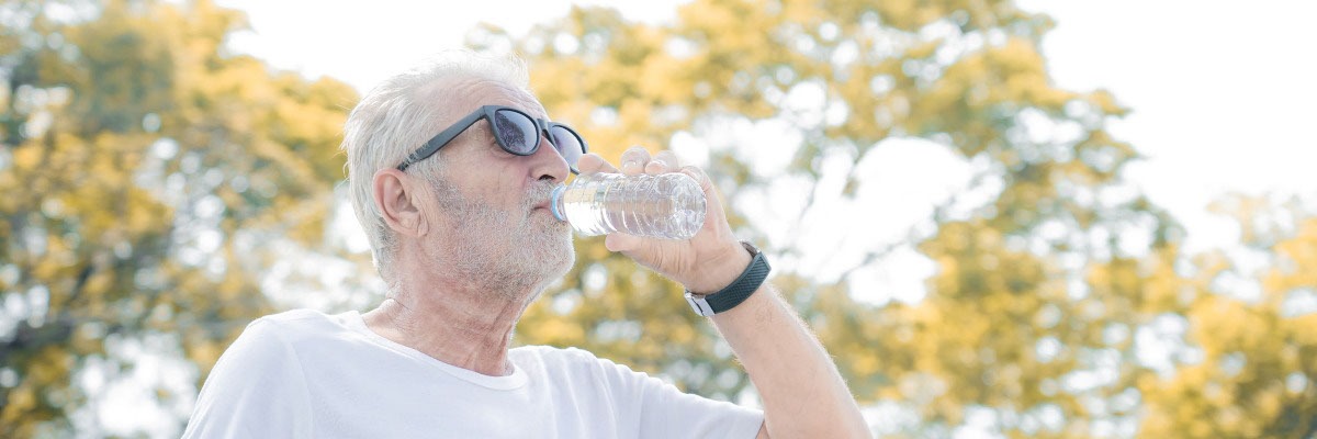 Man with dry eye wears sunglasses and drinks water outside 