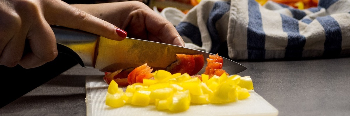 woman chopping yellow and red pepper